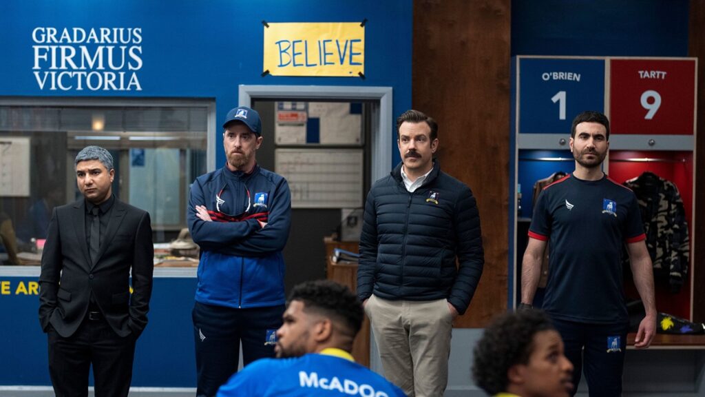 The AFC Richmond coaching staff with the "BELIEVE" sign seen in the background.